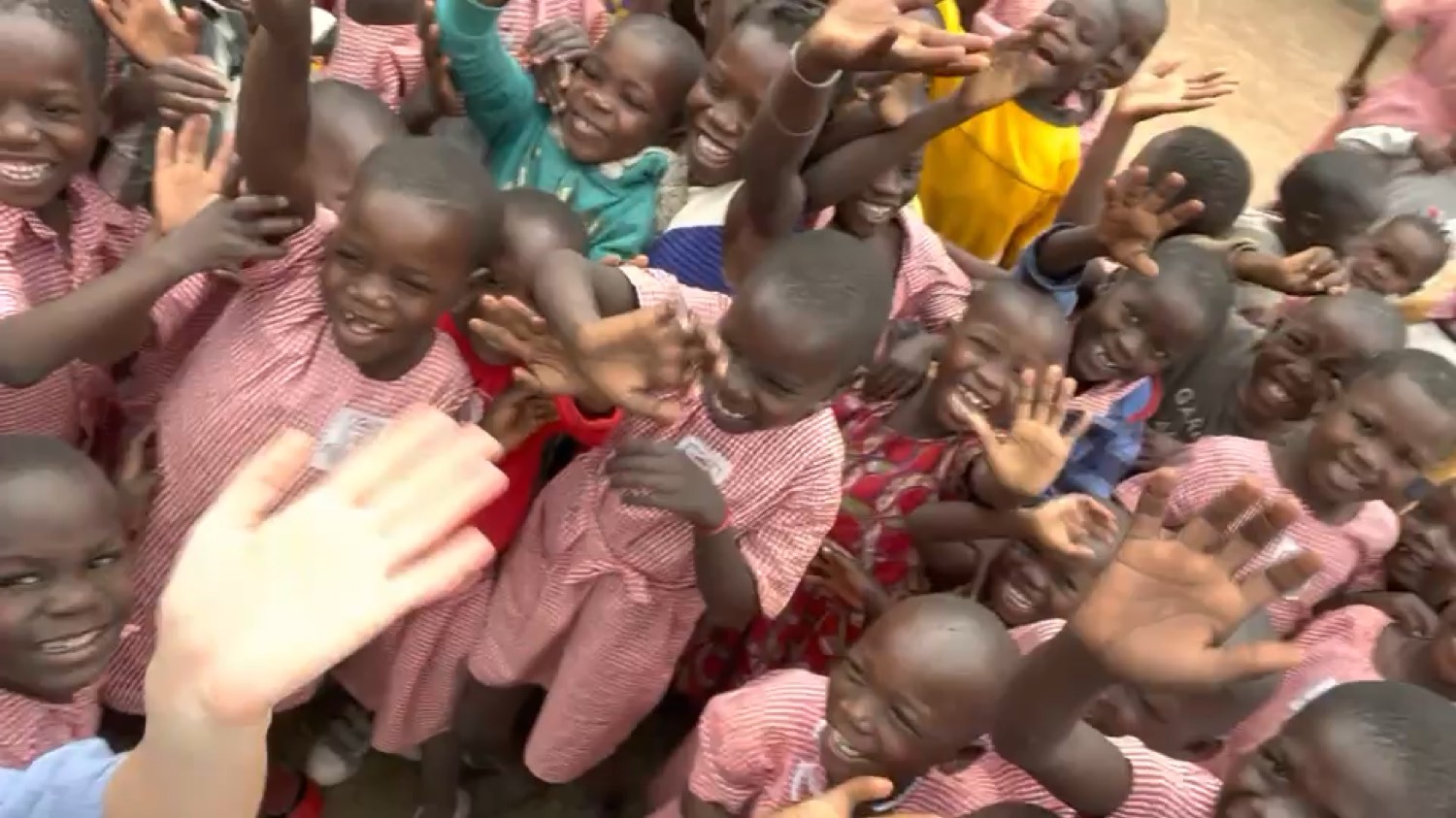 Kleuters van de Sikiliza Leo kleuterschool in Mulanda zwaaien lachend naar de camera.